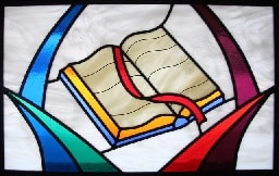 Stained glass window showing an open Bible