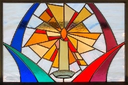Stained glass window showing a lit candle